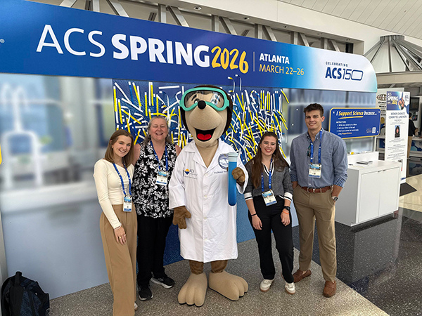Four attendees posing with a large mascot at the ACS Spring 2026 conference in Atlanta.